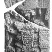 Black and white photograph of a Maya stela in four pieces. It depicts a standing man in regalia. The headdress in question is the top fragment.